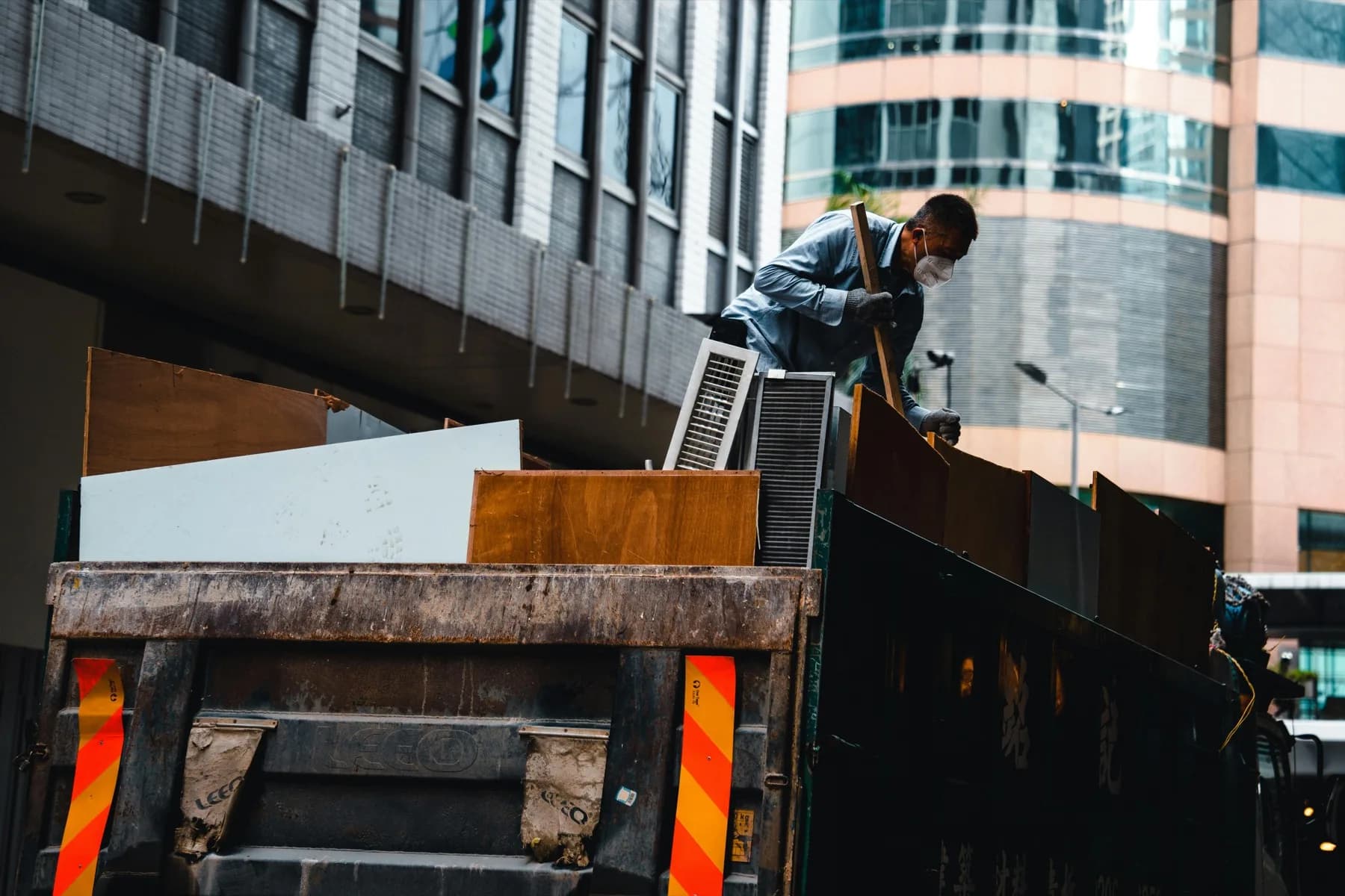 Worker loading construction debris into a roll-off dumpster — Wastebins.ca